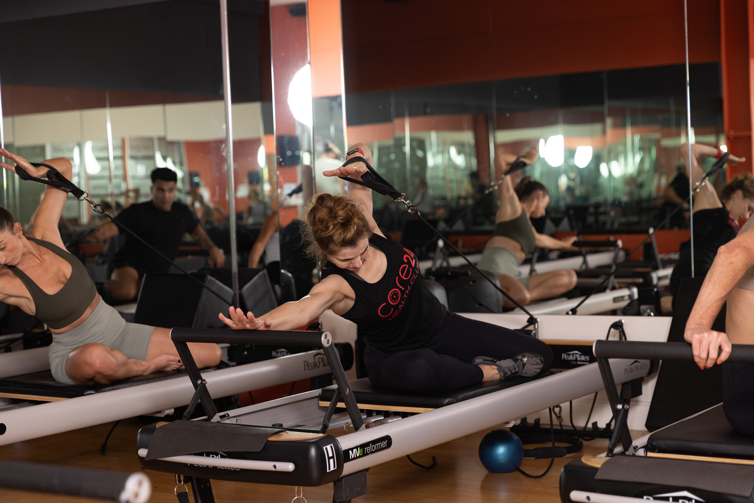 Group of people engaged in a Pilates reformer fitness class, performing exercises on the reformer machines at Core24 Gym.